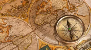 Bússola antiga de metal posicionada sobre um mapa mundi histórico envelhecido, evocando a era das grandes navegações, representando como estudar história do Brasil.