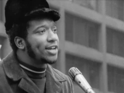 Fred Hampton, líder dos Panteras Negras em Chicago, discursando ao microfone com expressão carismática antes de ser assassinado pelo FBI.