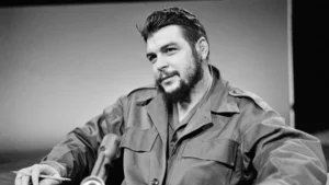 Uma foto de Ernesto Che Guevara sentado, com um microfone em sua frente, olhando para frente com um breve sorriso, representando o artigo "Che Guevara matava homossexuais?"